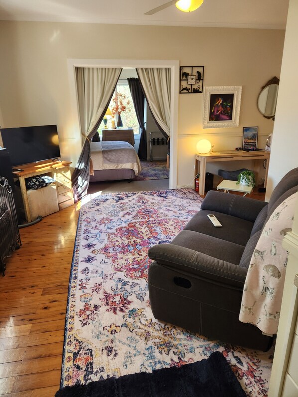 Een hotelkamer met een bed, een sofa, een bureau, een televisie en een groot vloerkleed met bloemen.