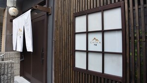 Un edificio japonés tradicional con puerta corredera, ventana con vidrio esmerilado y un farol colgante.