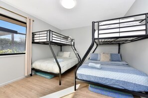Ein Zimmer mit zwei Etagenbetten, einem mit Vorhängen versehenen Fenster und Blick auf Grünflächen.