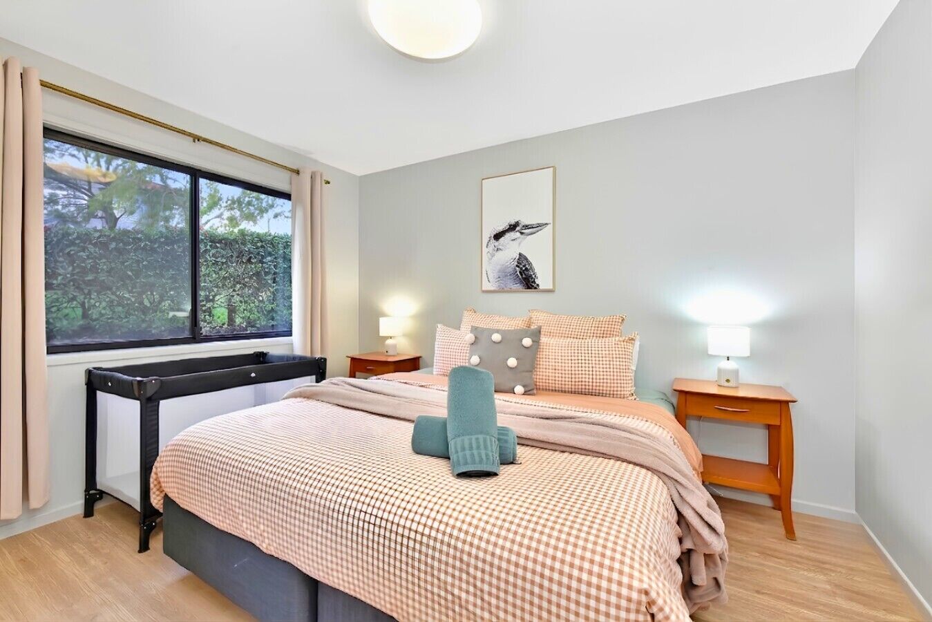A bedroom with a bed, bedside tables, a chair, a window, and a wall-mounted picture.