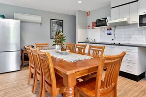 Una cocina compacta con armarios blancos, microondas y refrigerador.