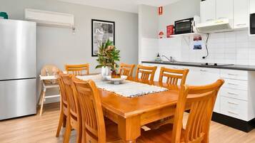 A modern kitchen with white cabinets, a built-in microwave, and a stainless steel refrigerator.