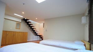 A bedroom with two beds, a wooden wardrobe, and a staircase.