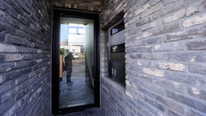 A narrow brick corridor with a glass door leading to a staircase.