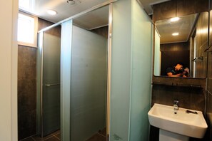 A modern bathroom with a glass partition, a sink, and a mirror. - Hannah Guest House - Hostel (Jeju City)