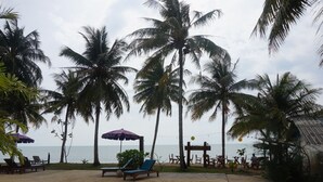 A beachside resort with palm trees, a pool, lounge chairs, and a view of the ocean. - Anandah Beach Resort (Takua Pa)