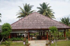 A rustic building with a thatched roof, surrounded by lush greenery and palm trees. - Anandah Beach Resort (Takua Pa)