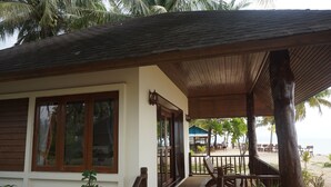 A beachfront property with a covered patio, wooden furniture, and potted plants. - Anandah Beach Resort (Takua Pa)