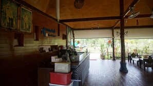 A restaurant interior with wooden walls, a counter with various items, and a view of the outdoors. - Anandah Beach Resort (Takua Pa)