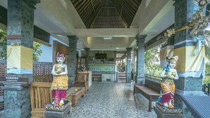 A covered walkway with stone statues, a reception desk, and a tiled floor.