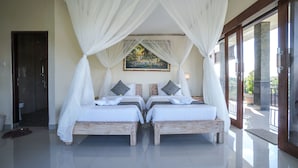 A room with two beds, a large painting on the wall, and a view of the outside through a glass door.