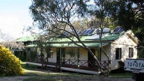 Een gelijkvloers huis met een groen dak, een veranda met een hekwerk en zonnepanelen.