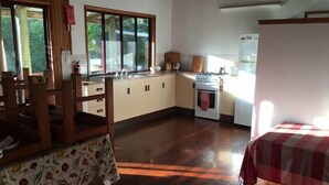 Een keuken met houten kastjes, een fornuis en een raam met uitzicht op groen.