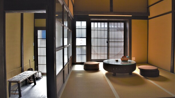 A traditional Japanese room with tatami flooring, a low table, and a round table with cushions. - Chika Rakuen (Kyoto)