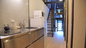 A modern kitchen with stainless steel appliances, a white tiled backsplash, and a wooden floor. - Chika Rakuen (Kyoto)