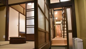 A traditional Japanese room with tatami flooring, a low wooden bench, sliding doors, and a ladder leading to a higher level. - Chika Rakuen (Kyoto)