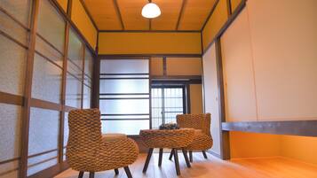 A traditional Japanese room with tatami flooring, sliding doors, and a low wooden ceiling.