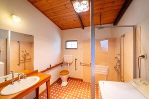 Ein Badezimmer mit Holzboden, einer Dusche, einer Toilette und einem Waschbecken.