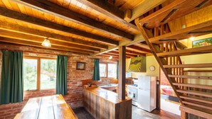 A rustic kitchen with wooden beams, a wooden counter, and a brick wall. - Grampians Pioneer stone cabin (Halls Gap)