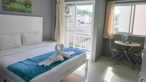 Une chambre d’hôtel avec un lit, un tableau au mur, un balcon avec vue et une petite table avec une bouilloire.