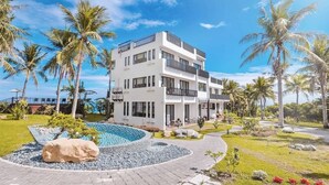 A modern multi-story hotel with a pool, surrounded by palm trees and a clear sky. - Rich Sunshine Inn (Beinan)