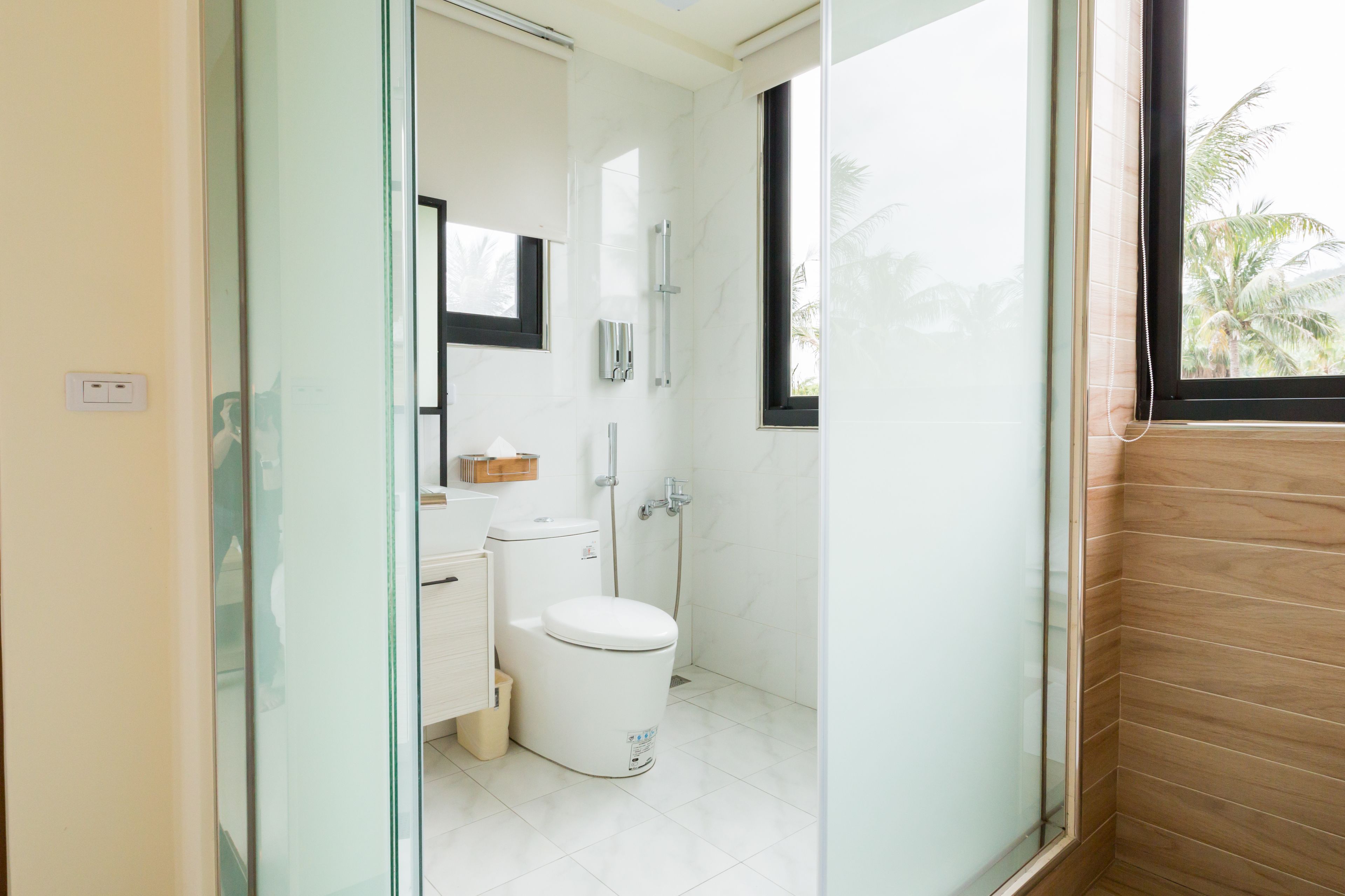A modern bathroom with a glass partition, a toilet, a sink, and a shower.