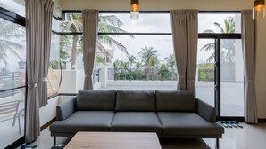 A modern living room with a grey sofa, a wooden coffee table, and large windows with curtains. - Rich Sunshine Inn (Beinan)