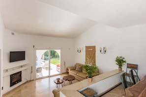 Amplia sala de estar con chimenea, televisor, sofá y una mesa de centro.