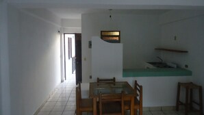 Un comedor con mesa y sillas, una encimera de cocina y un pasillo que conduce a otra habitación.