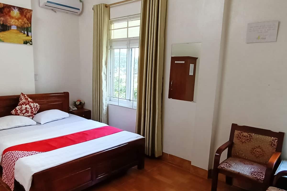 A neatly arranged bedroom with a wooden bed, a chair, a window with curtains, and a painting on the wall.