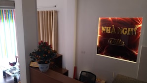 Ein Empfangsbereich mit einem Blumentopf, einem Vorhang und einem an der Wand befestigten Schild.