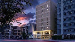A multi-story hotel with a ground-floor restaurant and a well-lit entrance. - Travelier Hostel (Bangkok)