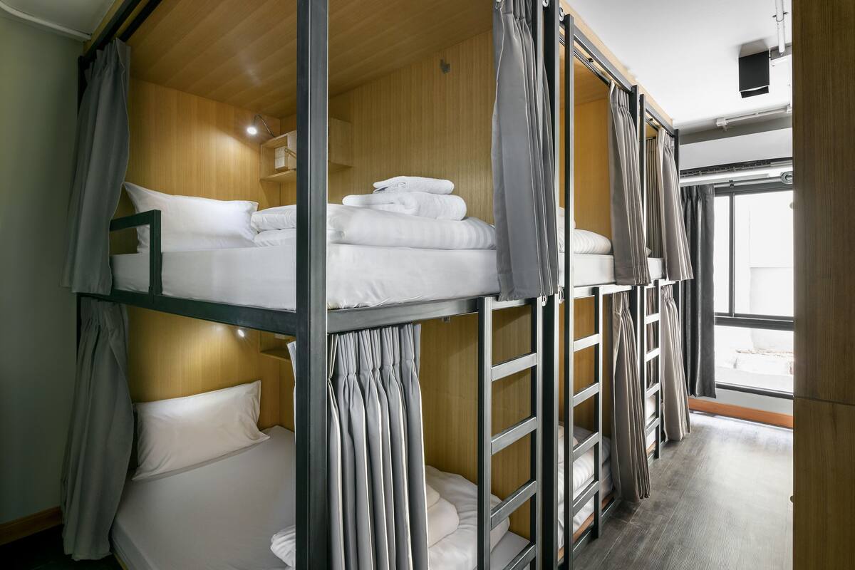 A bunk bed room with wooden walls, a window, and curtains.