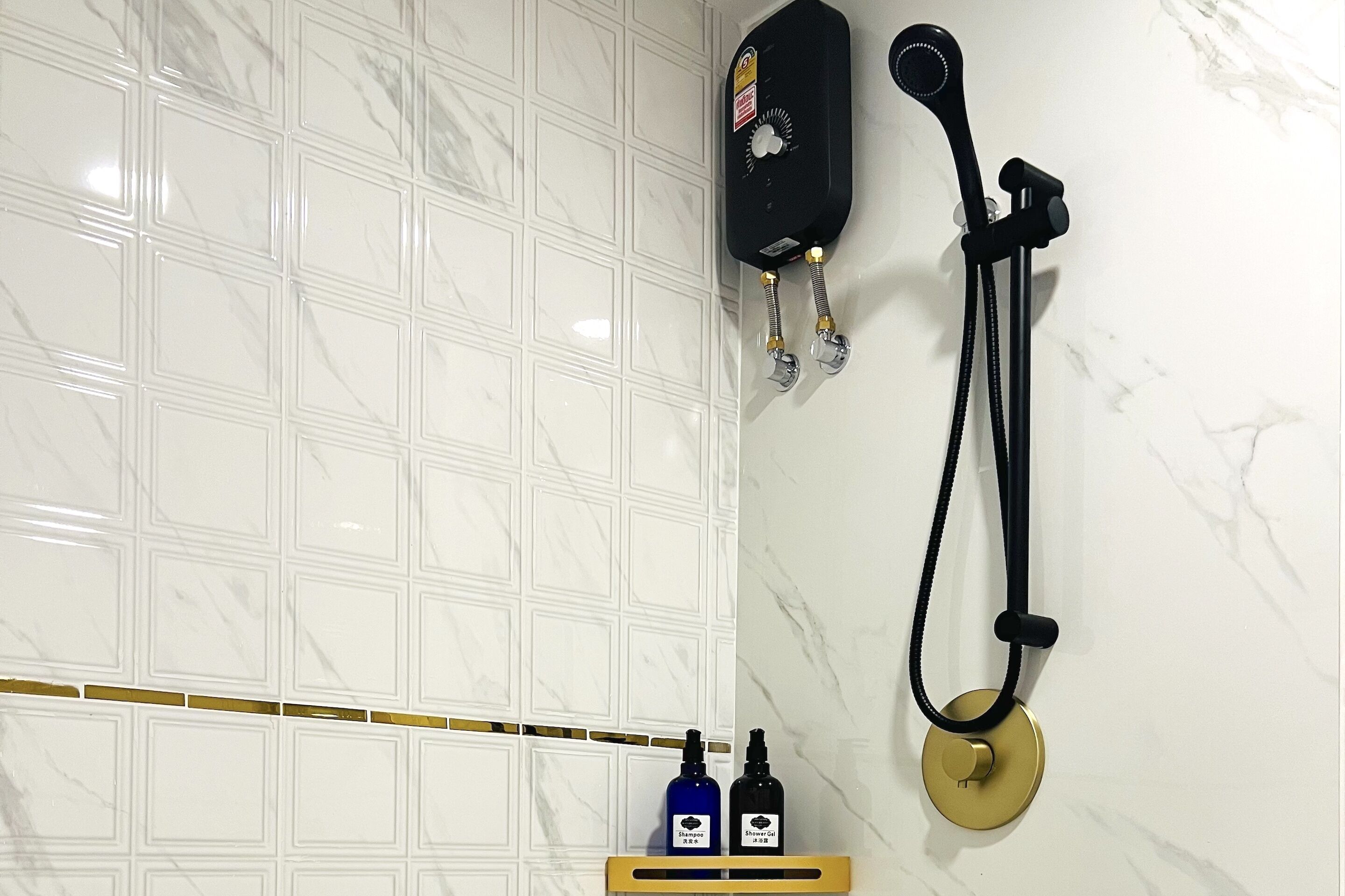 A bathroom with a white tiled wall, a black handheld showerhead, and two bottles on a shelf.