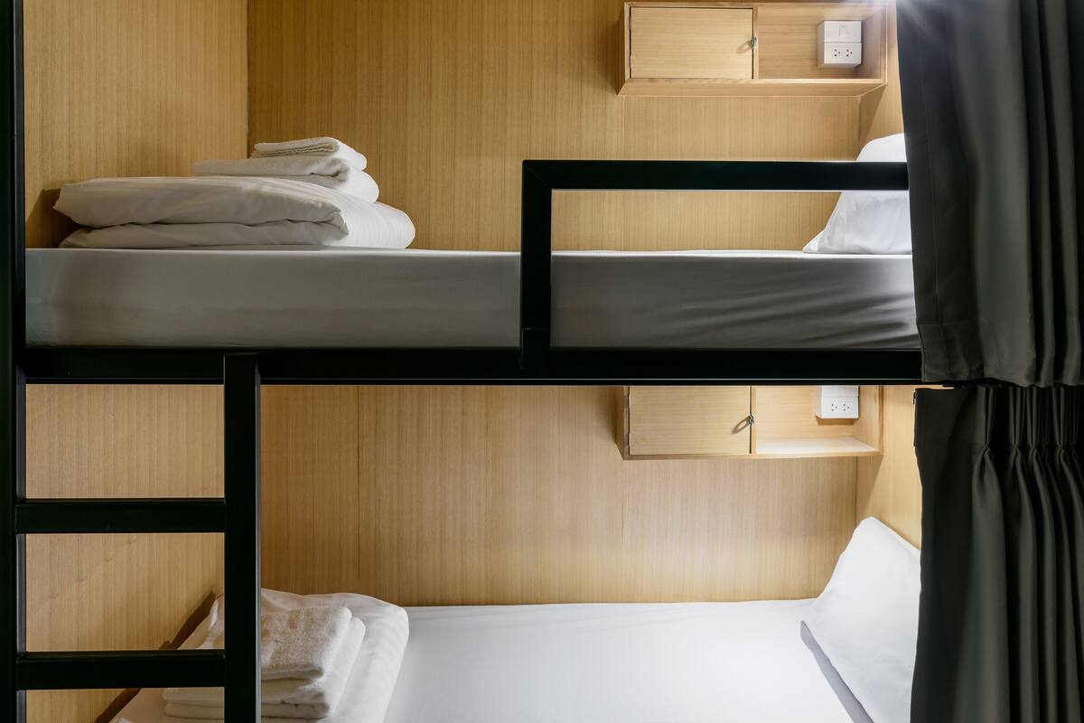 A bunk bed room with wooden walls, a small wooden cabinet, and a power outlet.