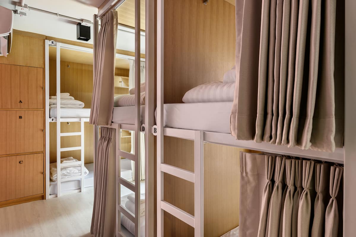 A hotel room with a bunk bed, wooden wardrobe, and a curtain.