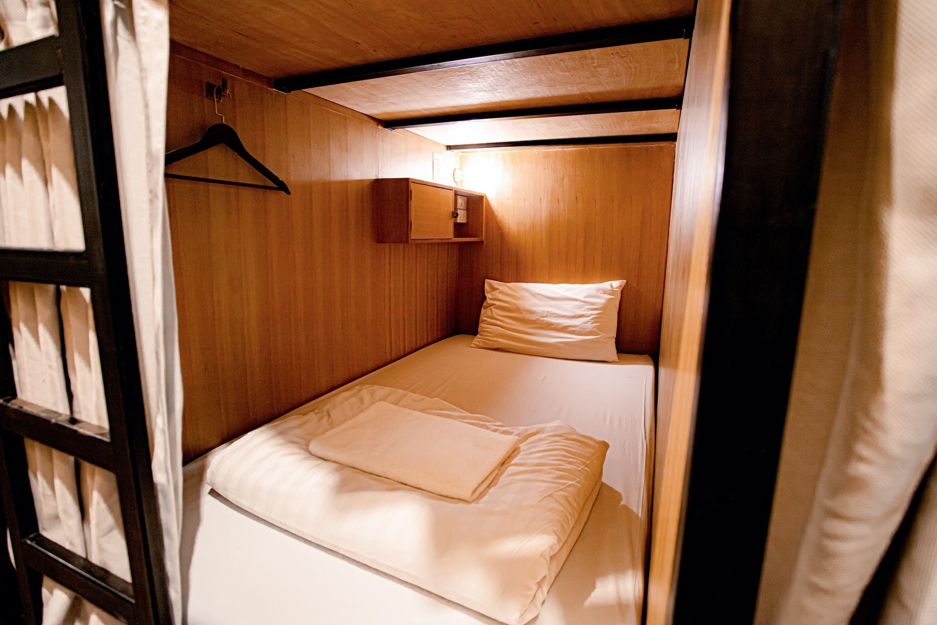 A small, cozy room with wooden walls and a single bed with white bedding.