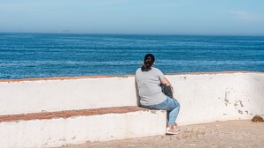 A person sitting on a white wall overlooking the sea. - Green Studio with private patio, 200 meters, 3 min by foot Beach of Peniche (Peniche)