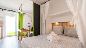 A hotel room with a bed, a table, and a chair. There is a green curtain and a white curtain. - Green Studio with private patio, 200 meters, 3 min by foot Beach of Peniche (Peniche)