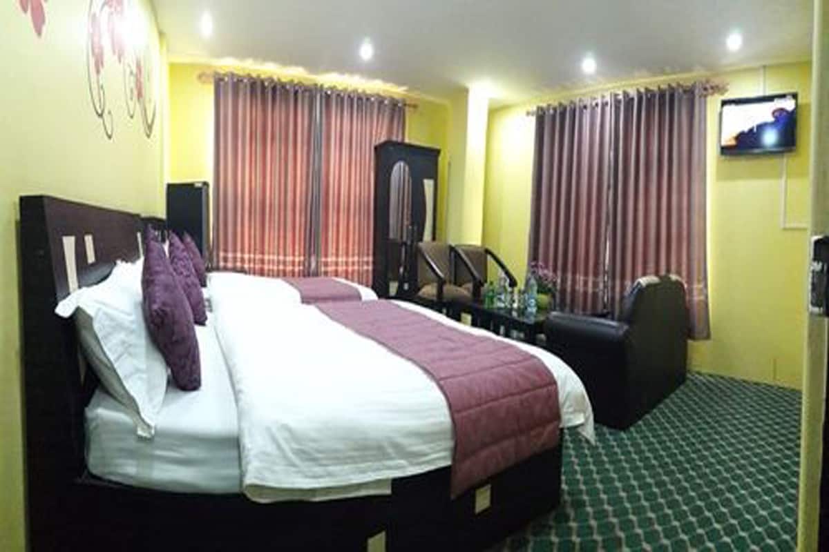 A hotel room with two beds, a TV, a desk, and a chair.