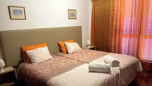Un lit double avec deux oreillers, une table de chevet avec une lampe et une fenêtre avec des rideaux.