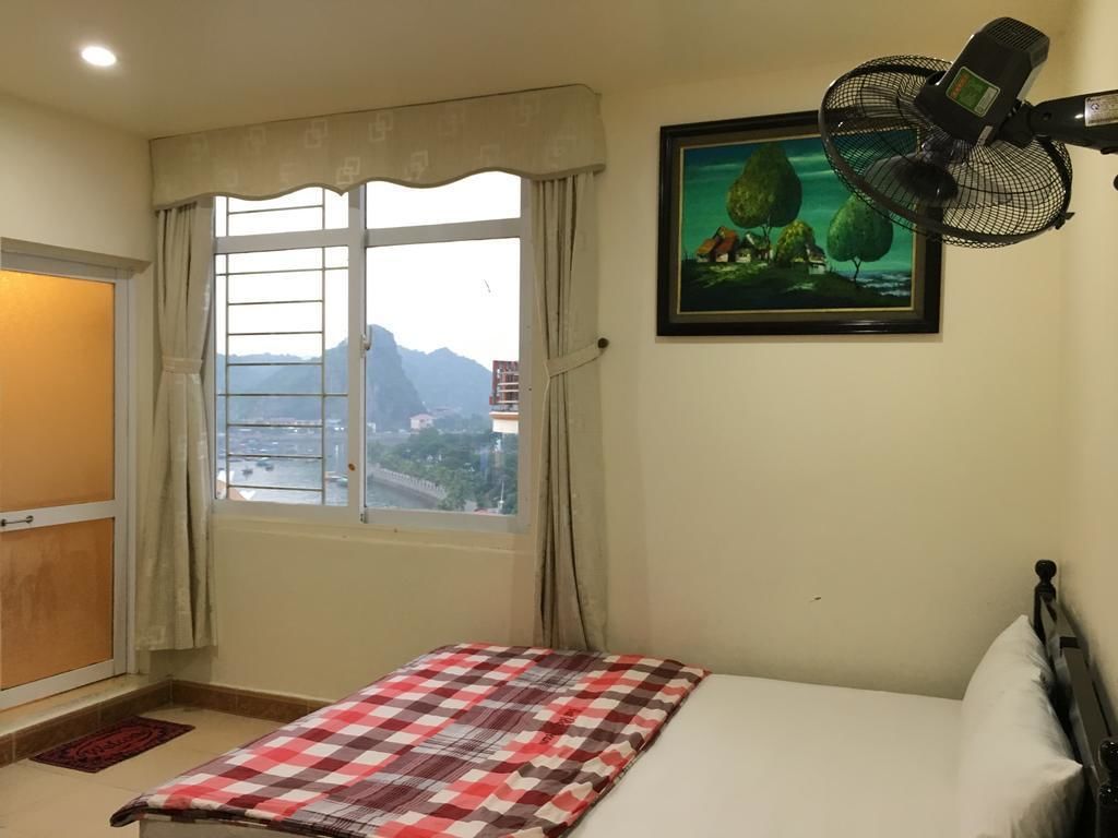 Un dormitorio con una cama, una ventana con cortinas, un ventilador de pared y un cuadro enmarcado.