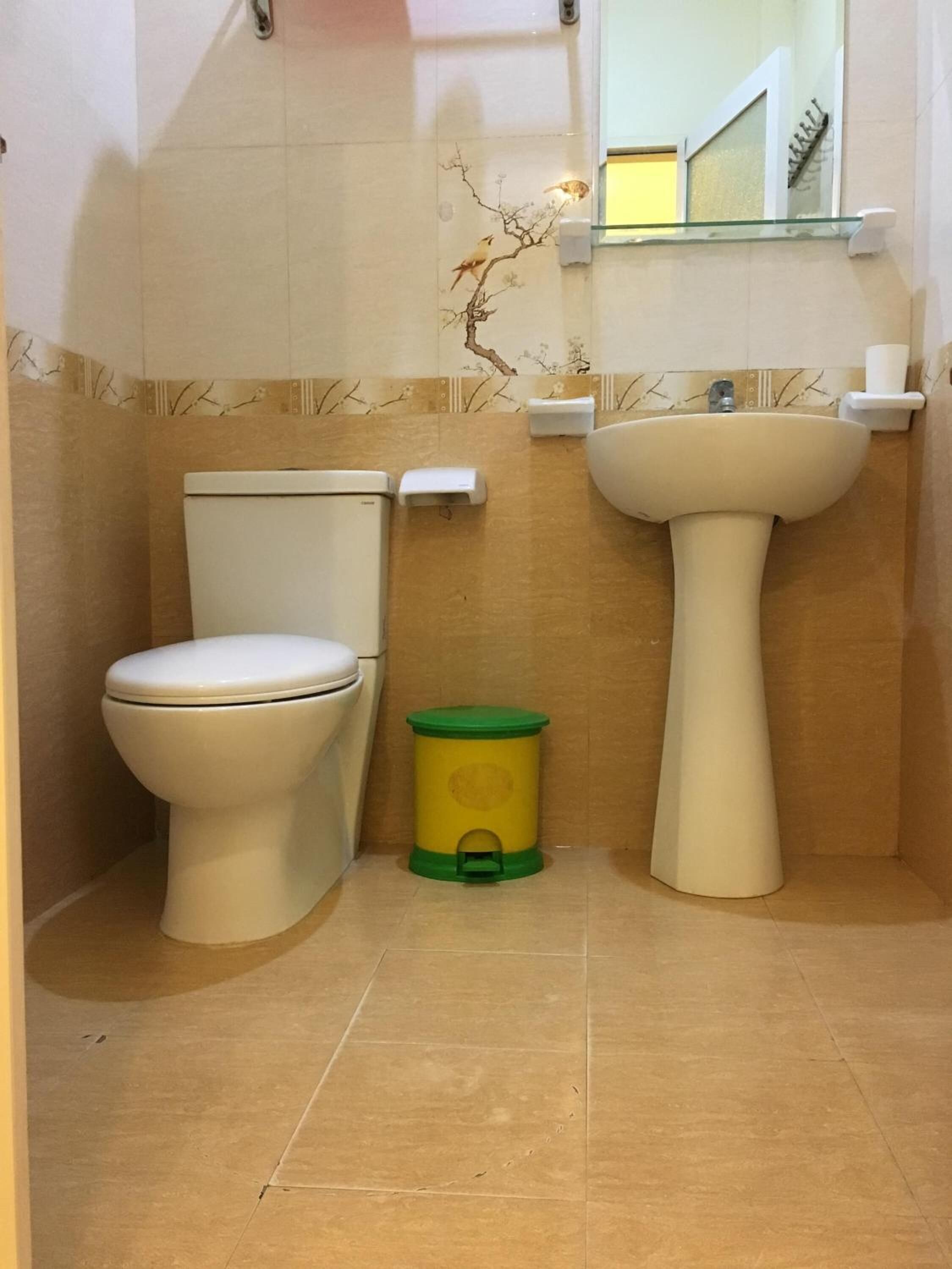 A bathroom with a toilet, sink, and trash bin.