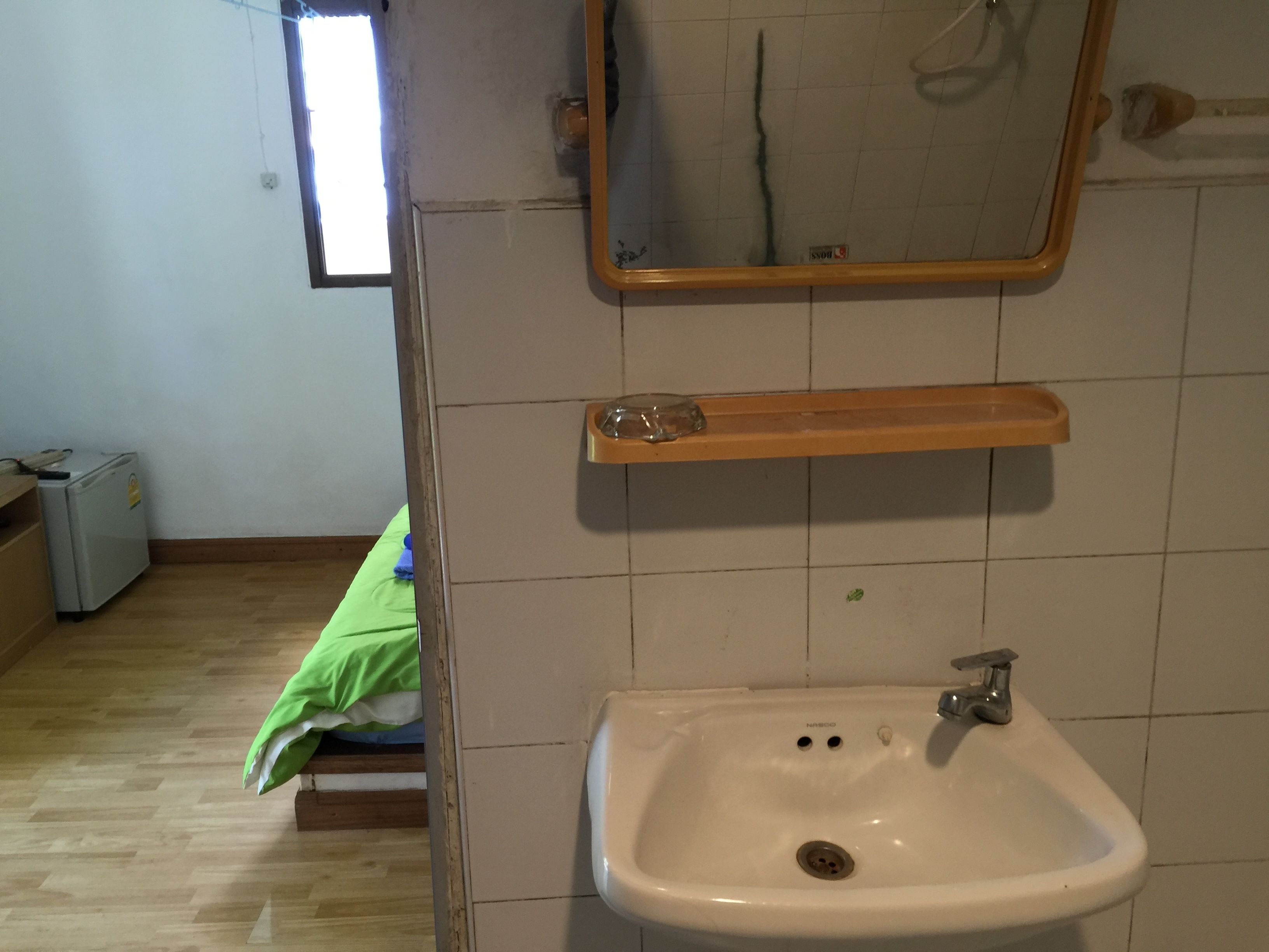 Un baño con lavamanos, espejo y estante superior.