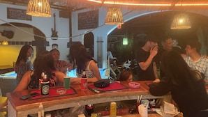 Una zona de bar con mostrador de madera, luces colgantes y una pizarra con el menú.