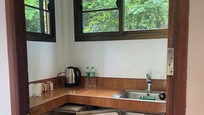 Una cocina compacta con refrigerador integrado, un lavamanos y una ventana con vistas a la vegetación.