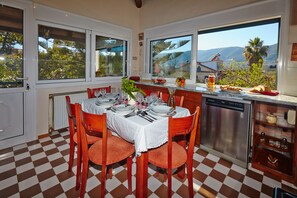 A kitchen with a checkered floor, a dining table set for four, and large windows overlooking a mountainous landscape.