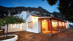Un edificio blanco con un patio cubierto, un ventanal grande y una puerta de acceso.
