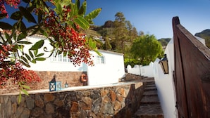 Un muro de piedra con un edificio blanco, una valla de madera y una escalera que sube.