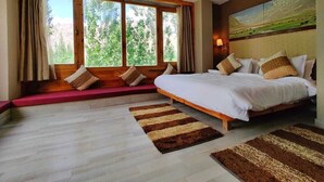Quarto com cama grande, um banco com almofadas e um quadro na parede.